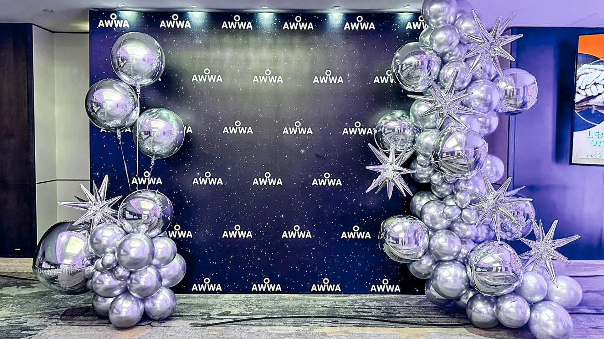 AIWA corporate event photo wall framed by silver balloons and festive star styling