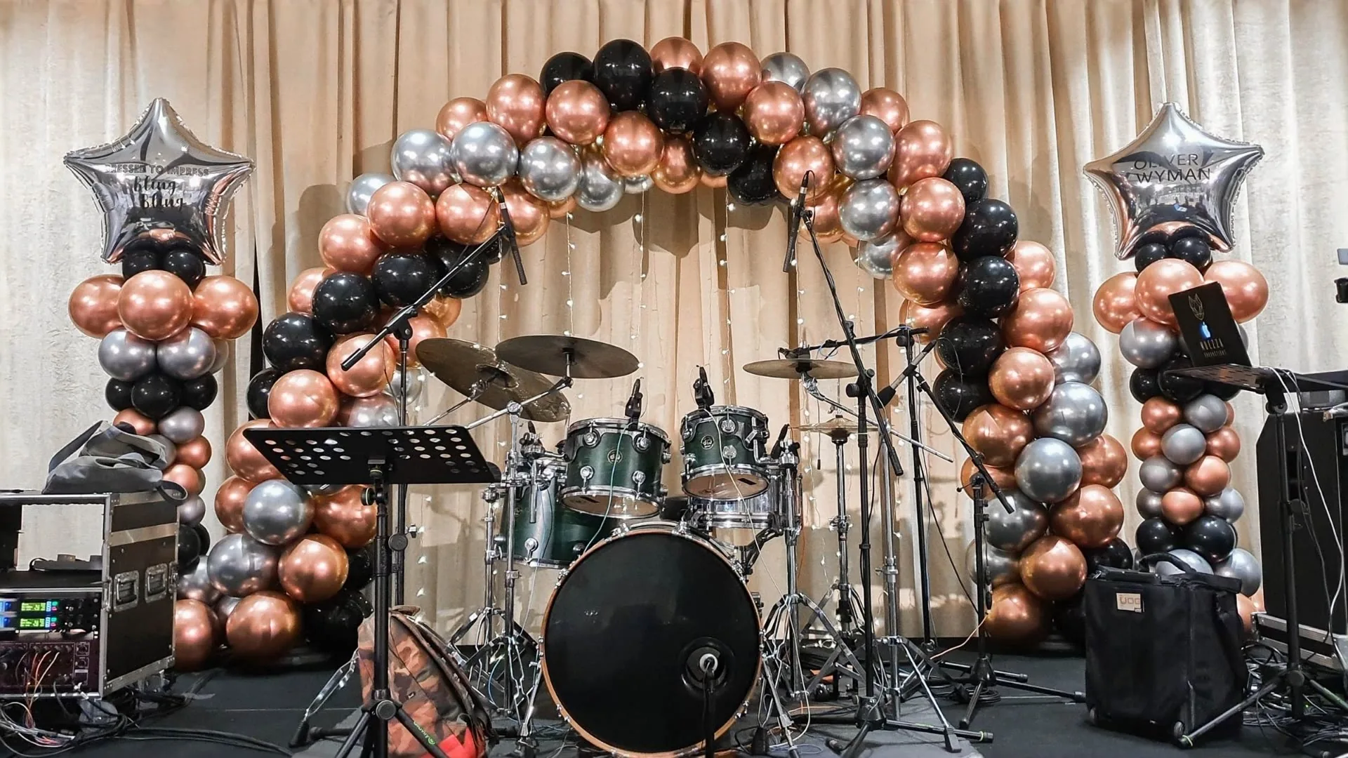 Live band instruments and a balloon-framed stage prepared for a corporate dinner and dance