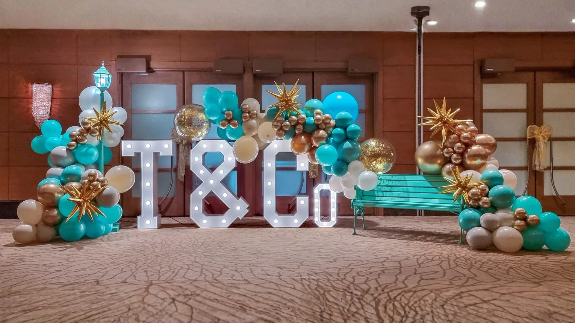Completed T and C corporate event photo area with turquoise, gold and white balloon styling