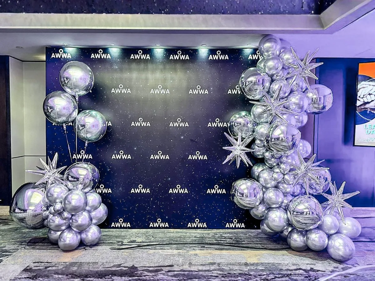 Branded reception photo wall with a chrome balloon installation by The Happier Event Company
